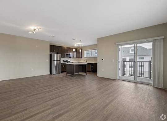 A spacious living room with a kitchenette and a dining table.