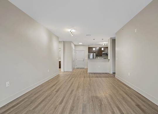 A long, empty hallway with wood flooring and white walls.