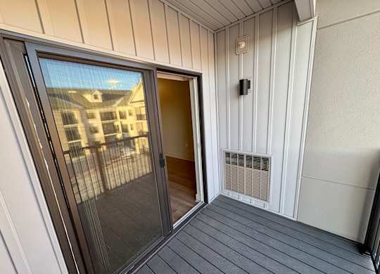 A balcony with a glass door and a heater vent.