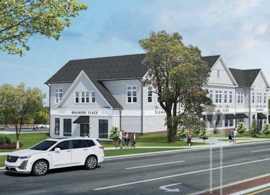 A white car is driving on a road next to a building with a sign that says