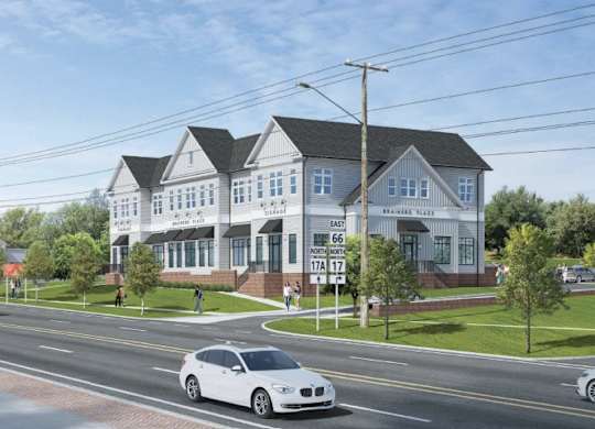 A white car is driving on a street past a house.