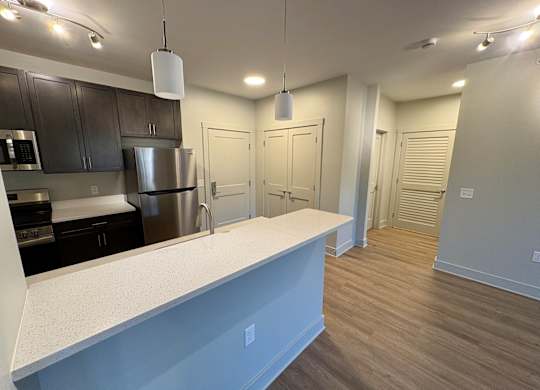A kitchen with a white counter top and stainless steel appliances.