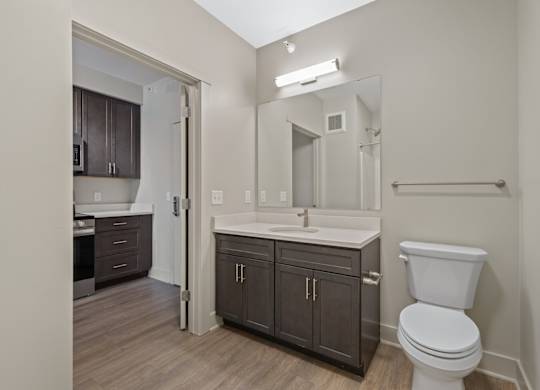 A bathroom with a toilet, sink, and mirror.