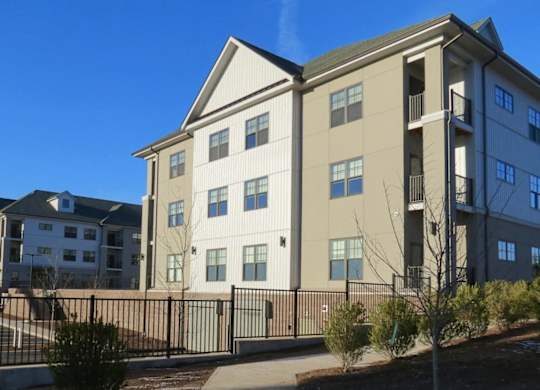 A large apartment complex with a black fence in front.