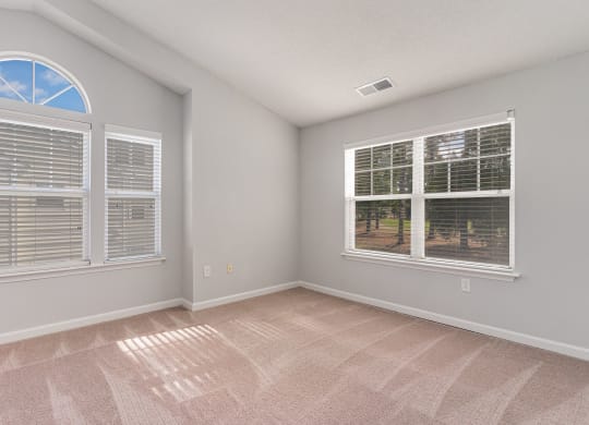 an empty living room with windows and carpeting