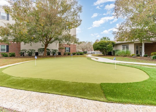 a putting green in front of a house with trees and condos at Litchfield Oaks Apartments, Pawleys Island