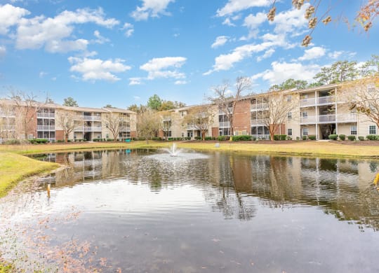a pond with a fountain in front of an apartment building at Litchfield Oaks Apartments, Pawleys Island