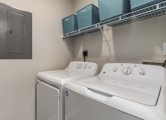 a white washer and dryer in a laundry room with a shelf above it at Litchfield Oaks Apartments, South Carolina, 29585