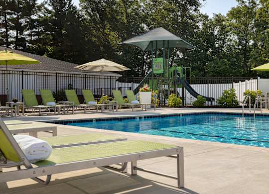 A pool with a slide and sun loungers.