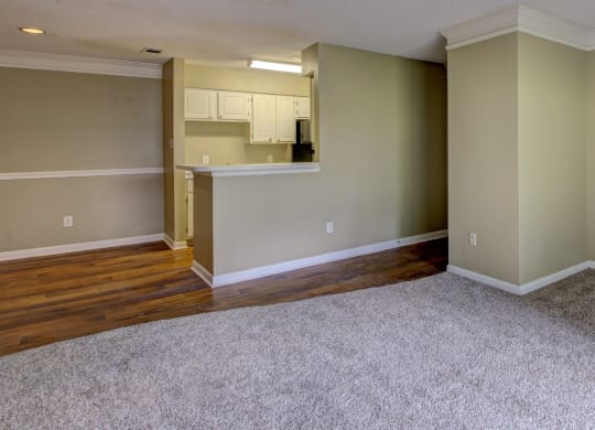 an empty living room with carpet and a kitchen