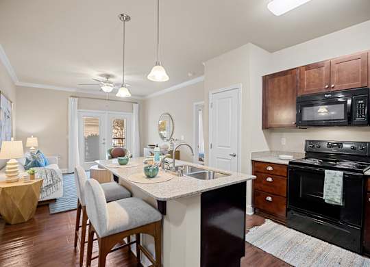 A kitchen with a black stove and wooden cabinets.