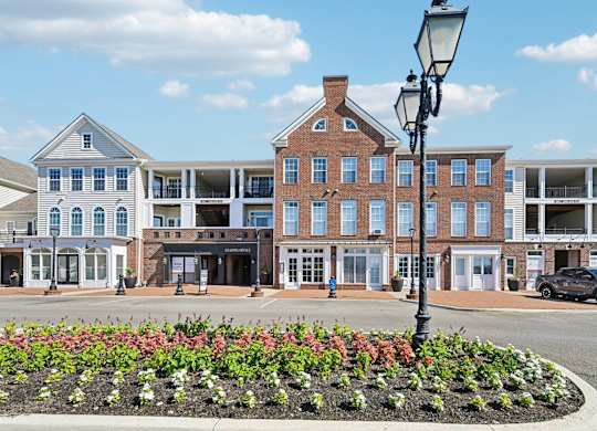 A street view of a town with buildings, cars, and a flower bed.