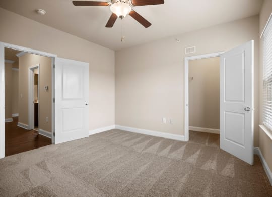 an empty living room with carpet and a ceiling fan