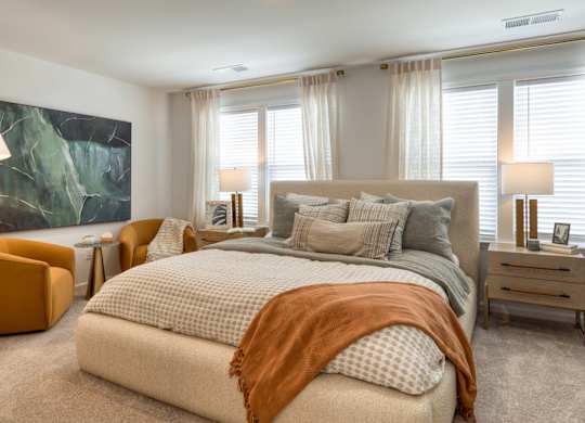 A bedroom with a large bed and a painting on the wall at The Mark Townhomes Apartments, Harrisonburg, VA