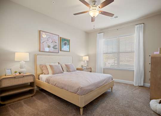 A bedroom with a bed, nightstand, and a ceiling fan.