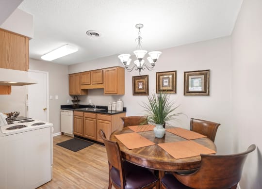 a dining area with a table and chairs and a kitchen in the background