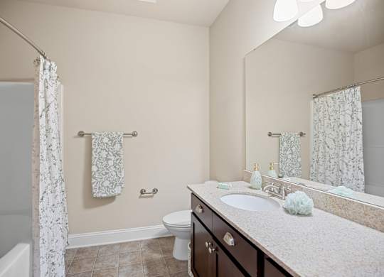 A bathroom with a white sink, toilet, and a bathtub with a white curtain.