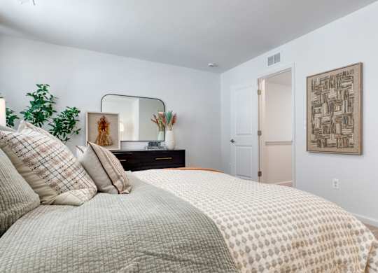 A bedroom with a large bed and a mirror on the wall at The Mark Townhomes Apartments, Harrisonburg