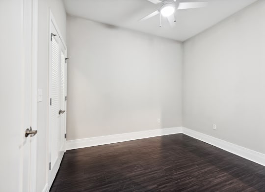 a bedroom with a hardwood floor and a ceiling fan