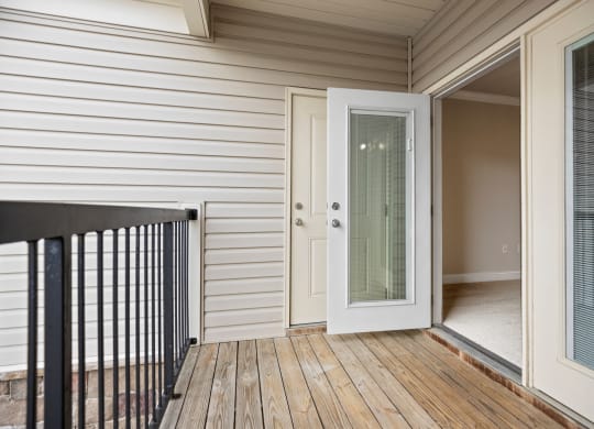 the deck of a home with a door open to a balcony