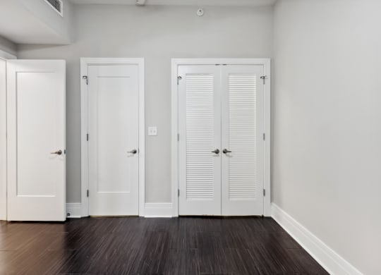 a bedroom with three doors and a hardwood floor