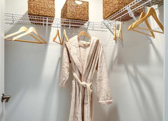 A white closet with a robe hanging on a hanger at The Mark Townhomes Apartments, Harrisonburg, Virginia