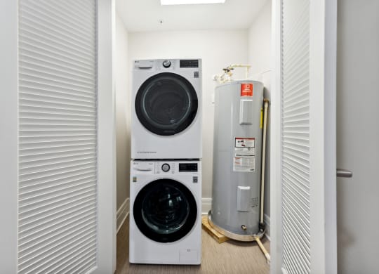 a washer and dryer in a small room next to a water heater