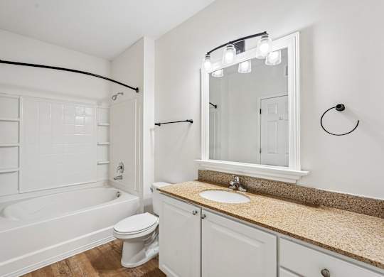 A white bathroom with a tub, toilet, sink and mirror.