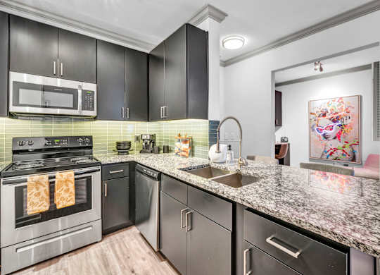 A modern kitchen with granite countertops and stainless steel appliances.