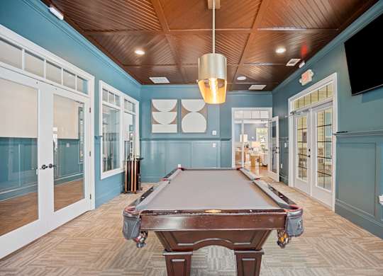 A pool table is in the middle of a room with a wooden ceiling.