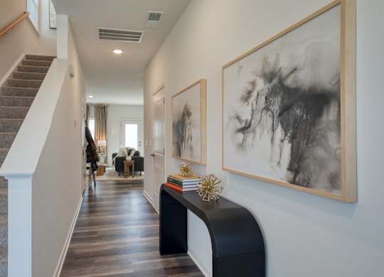A hallway with a staircase and two framed pictures on the wall at The Mark Townhomes Apartments, Harrisonburg