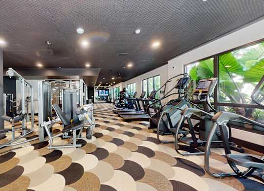 A gym with a variety of equipment including treadmills, weights, and exercise machines.