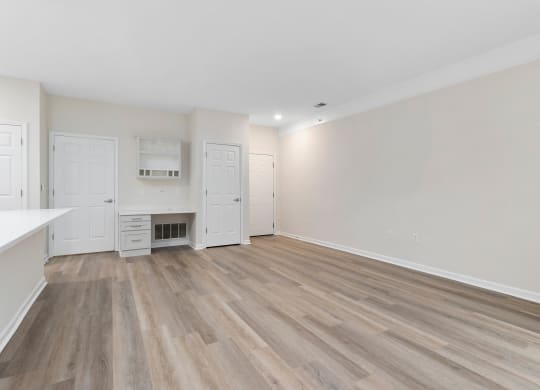 an empty living room and kitchen with white walls and wood flooring  at The Charleston, Columbus