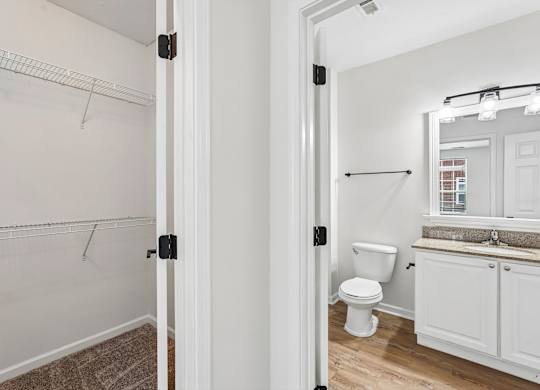 A white bathroom with a toilet, sink, and a mirror.