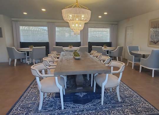 A dining room with a large table and chairs.