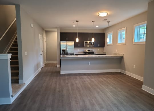 an empty living room with a kitchen in the background at Barclay Place Apartments, Wilmington, NC, 28412