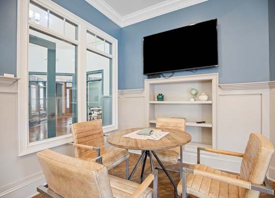A room with a table and chairs and a television.