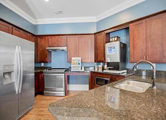 A kitchen with a granite counter top and stainless steel appliances.