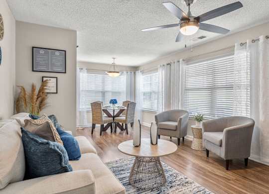 A living room with a beige sofa, a coffee table, and a ceiling fan.