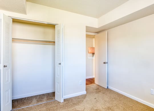 an empty bedroom with a closet and a hallway to a bathroom
