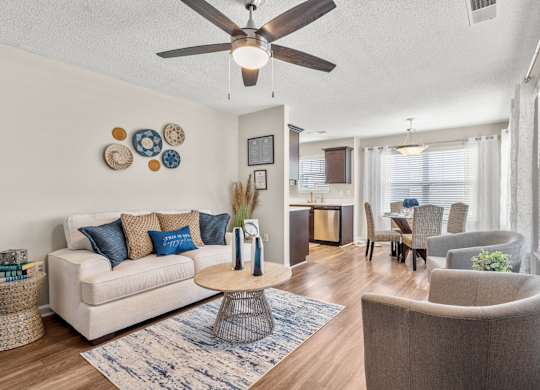 A living room with a white couch, a coffee table, and a ceiling fan.