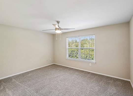A room with a ceiling fan and a window with blinds.