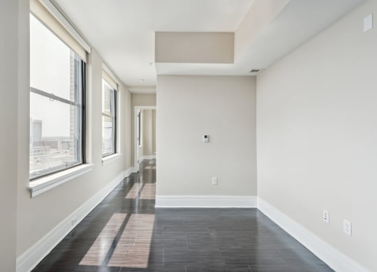 an empty room with large windows and a black tile floor