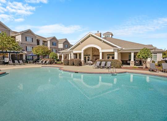 A large swimming pool in front of a building with a covered patio area.