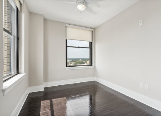 an empty bedroom with a window and a ceiling fan