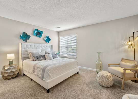 A bedroom with a large bed, a chair, and a lamp.