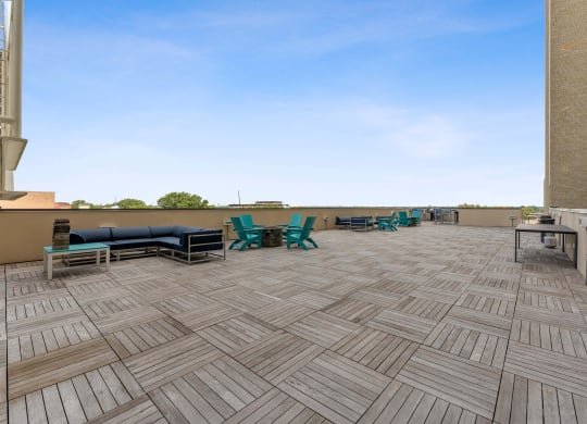 a patio with a grill and lounge chairs on top of a building
