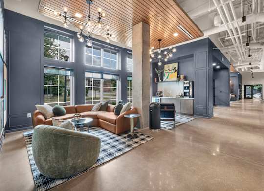 A spacious living room with a large grey couch and a grey armchair.