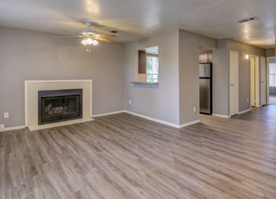 an empty living room with a fireplace and a ceiling fan