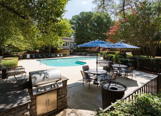 a backyard with a pool and patio with chairs and umbrellas